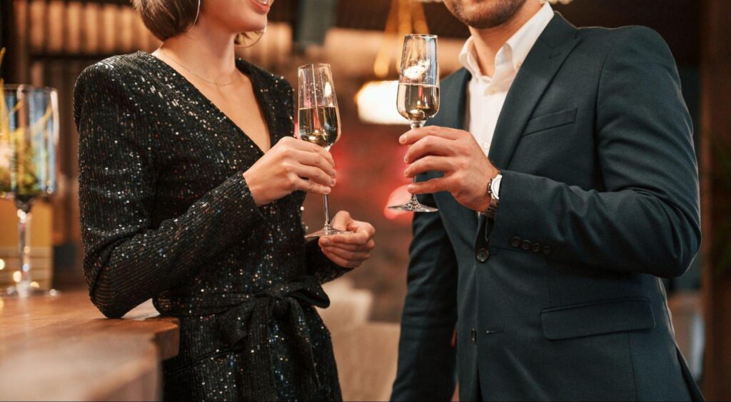 ouple holding champagne wearing black formal attire